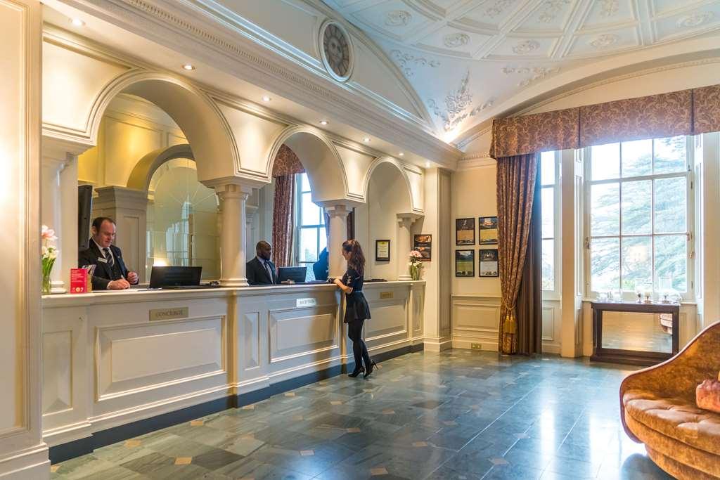 فندق ماكدونالد باث سبا المظهر الداخلي الصورة The photo shows the interior of a hotel reception area. There is a stylish front desk with several staff members attending to guests. A woman is interacting with one of the receptionists. The design features elegant architectural details, including a