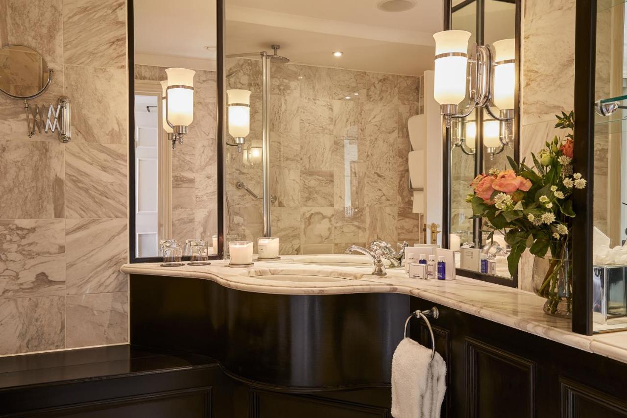 فندق ماكدونالد باث سبا المظهر الخارجي الصورة The photo shows a luxurious bathroom featuring elegant design elements. There is a curved marble countertop with a sink, complemented by stylish silver fixtures. The walls are adorned with light-colored marble, creating a sophisticated ambiance. Seve