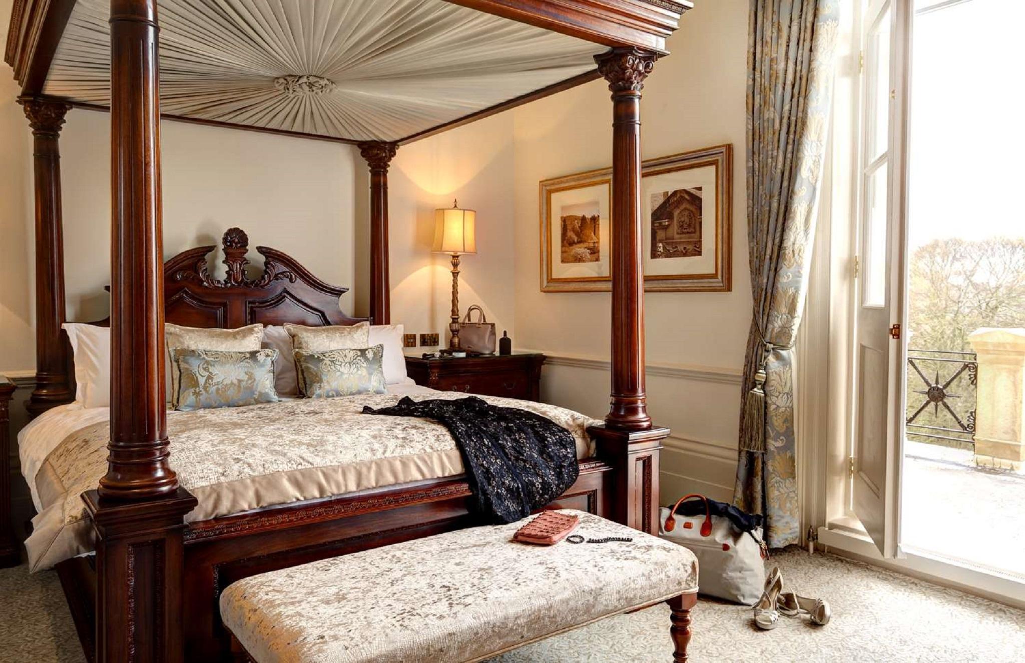 فندق ماكدونالد باث سبا المظهر الخارجي الصورة The photo depicts a beautifully designed bedroom featuring a four-poster bed with a decorative canopy. The bed is dressed with elegant bedding and several patterned pillows. Adjacent to the bed, there is a matching wooden nightstand with a stylish la