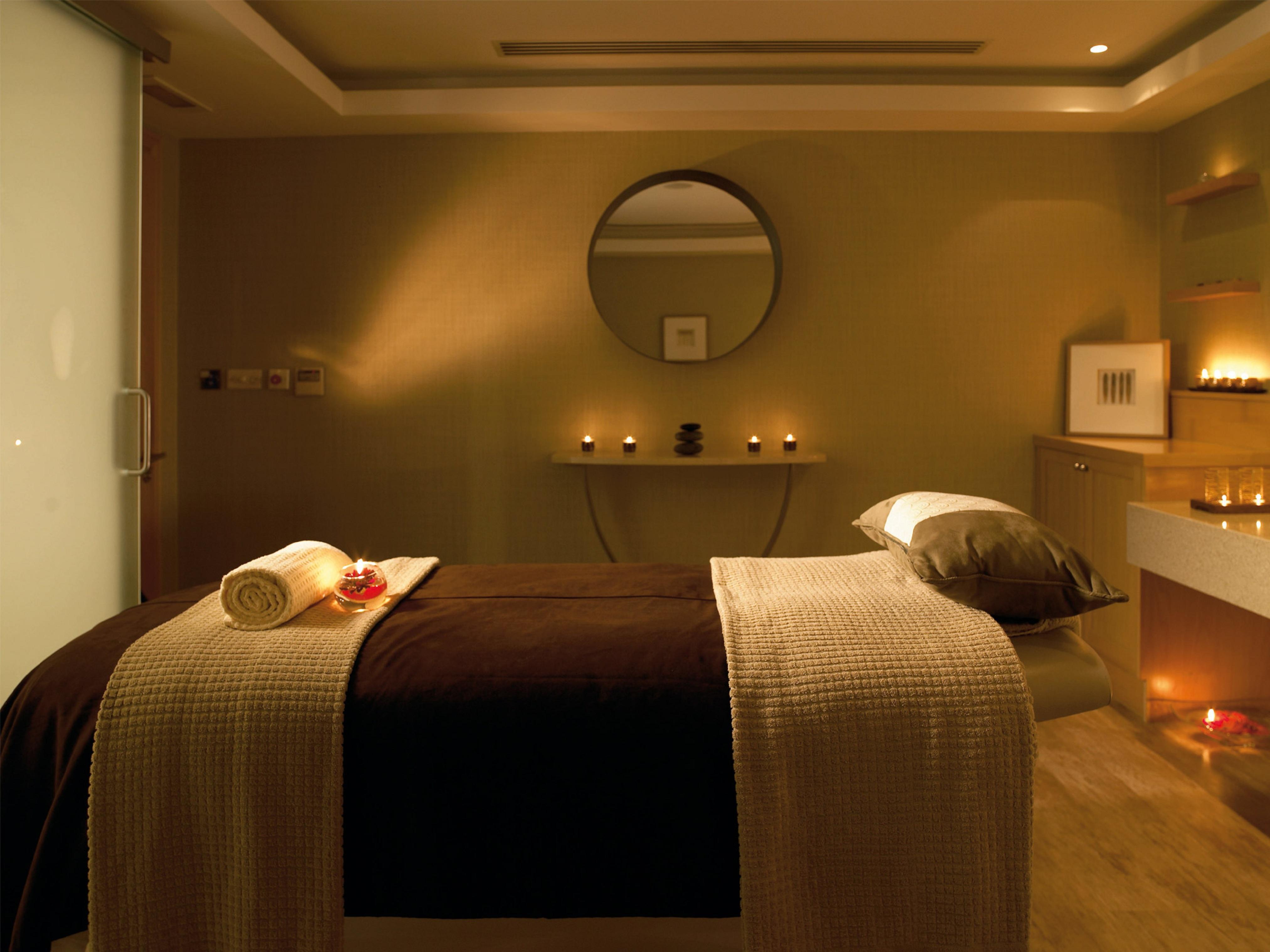 فندق ماكدونالد باث سبا المظهر الخارجي الصورة The photo shows a serene spa room designed for relaxation and wellness. A comfortable massage table is centered in the room, covered with a soft, neutral-toned blanket. On the table, there is a rolled towel and a few decorative elements, possibly flo