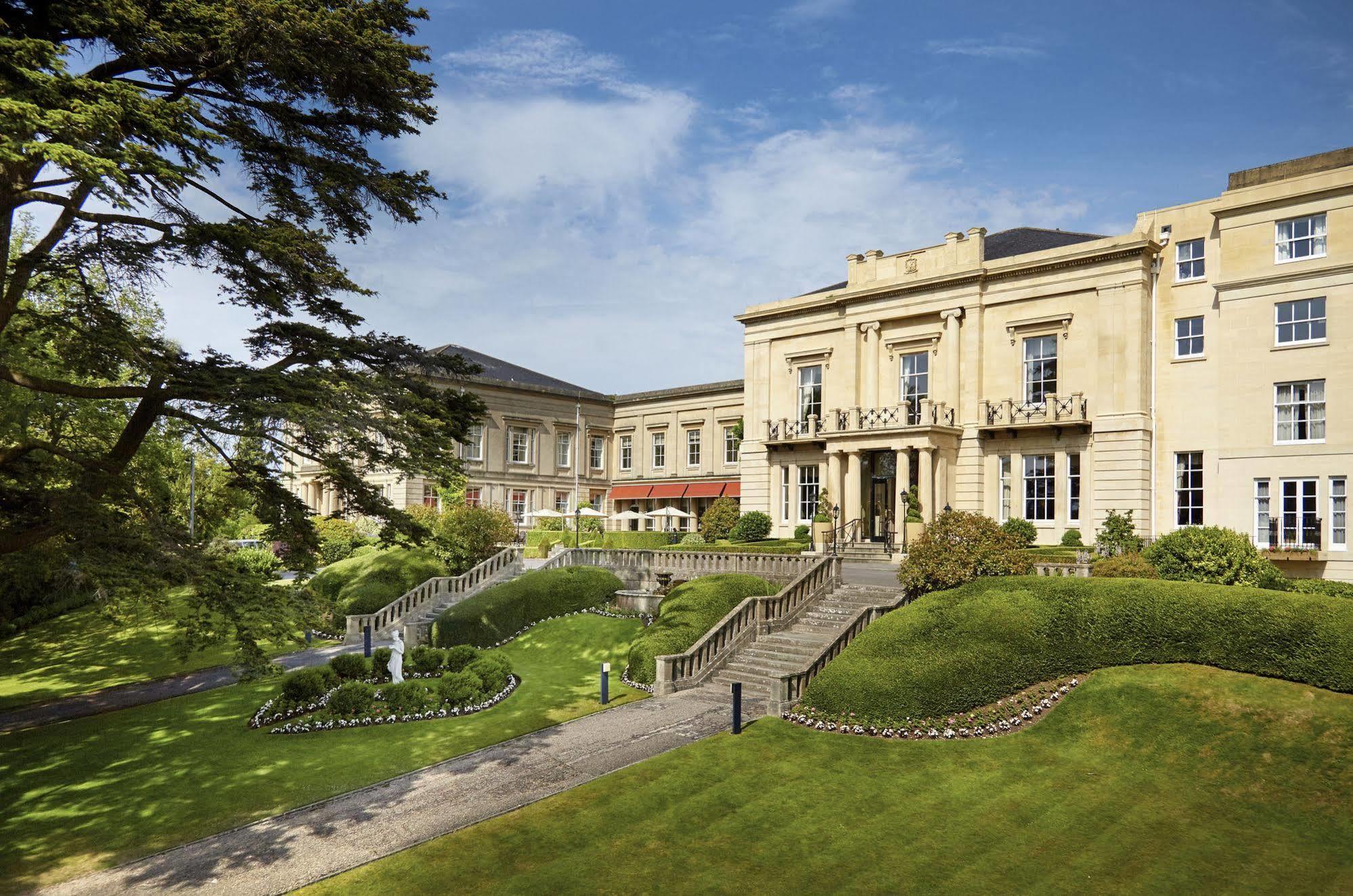فندق ماكدونالد باث سبا المظهر الخارجي الصورة The photo shows a grand building, likely a hotel or estate, surrounded by well-manicured gardens and lawns. The architecture appears elegant, with multiple stories and large windows. There are steps leading up to the entrance, and the setting include